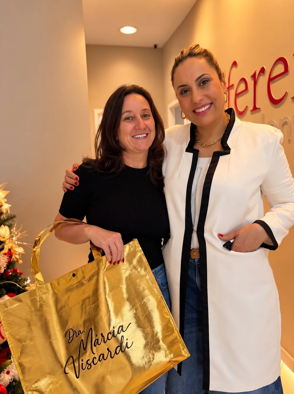 Paciente com a sacola dourada da Dra. Márcia Viscardi, abraçada a ela na recepção